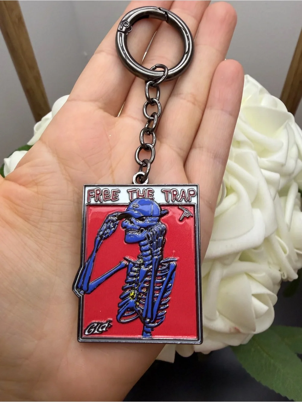Blue Skeleton 'Free The Trap' Enamel Keychain on Red Background